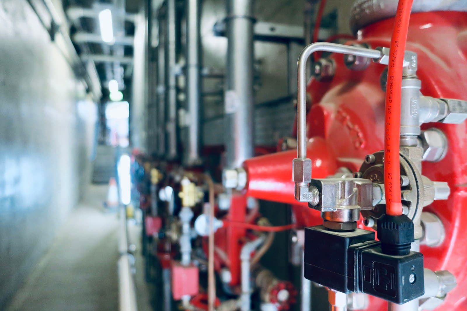 Commercial plant room with red pump sets and stainless pipework